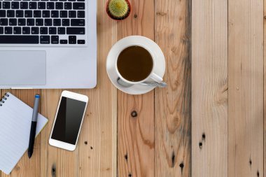 Not defteri, dizüstü bilgisayar, akıllı telefon ve kahve fincanı fare üst görünümü olan ofis eşyaları..