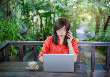 Asyalı kadın labtop ve smartphone açık bahçe kullanarak.