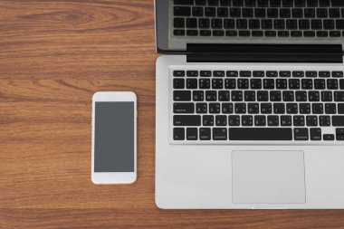 Laptop ve ahşap masa üstünde smartphone