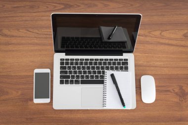 Laptop ve ahşap masa üzerindeki mali belgeler ile smartphone