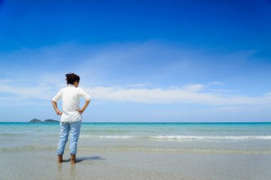 Okyanusa bakan ve günün tadını çıkaran bir kadının dikiz görüntüsü..