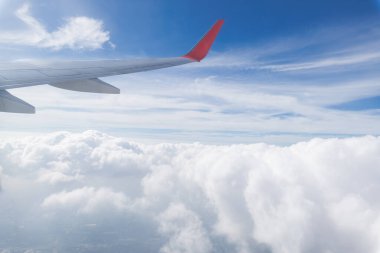 Bir uçak pencereden görüldüğü gibi gökyüzü ve bulutlar. Güzel mavi/mor/turuncu gökyüzü kanadında uçuş sırasında pencere uçak ile seyir.