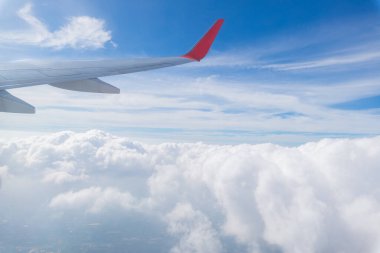 Bir uçak pencereden görüldüğü gibi gökyüzü ve bulutlar. Güzel mavi/mor/turuncu gökyüzü kanadında uçuş sırasında pencere uçak ile seyir.