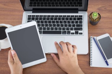 ofiste tabloda bir tablet bilgisayar ve laptop tutan eller