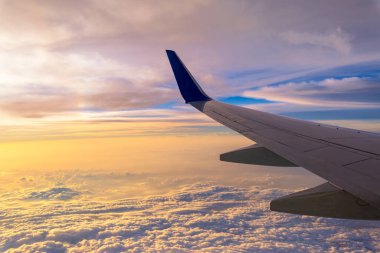 Bir uçak pencereden görüldüğü gibi gökyüzü ve bulutlar. Güzel mavi/mor/turuncu gökyüzü kanadında uçuş sırasında pencere uçak ile seyir.
