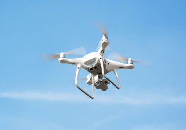 Beyaz dron açık mavi gökyüzünde süzülüyor