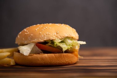 Peynirli hamburger ve ahşap masada kızarmış patates.