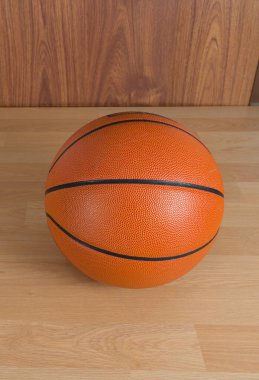 An official orange ball on a hardwood basketball court clipart