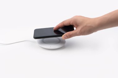 Cep telefonunu kablosuz şarja bağlıyorum, modern ekipman beyaz arka planda izole edilmiş.