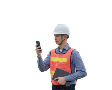 Güvenlik yeleği giymiş bir adam elinde bir cep telefonu ve bir kitap tutuyor.