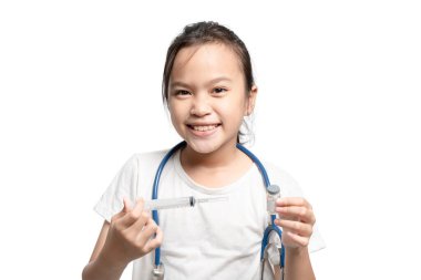 Genç bir kız elinde şırınga ve bir şişe tutuyor, gülümsüyor. Masumiyet ve merak kavramı, kızın tıbbi prosedürleri öğrenmesi veya sağlığıyla ilgilenmesi gibi görünüyor.