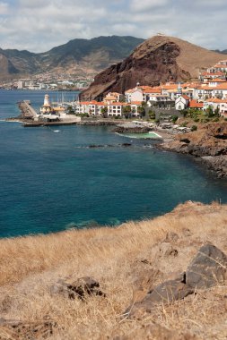 Kızıl Döşemeli Çatıları ve Dağ Arkaplanı olan Sahil Kasabası. Canial Madeira Portekiz.