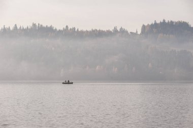 Güneşin doğuşunda Misty Gölü 'nde teknedeki balıkçılar. Czorsztyn Gölü Polonya.