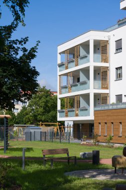 Peyzajlı iç avlusu olan modern bir apartman dairesi. Yeşil alanda bir çimen, genç bir ağaç ve eğri bir ahşap bank bulunuyor. Bu da sakinler için eğlence alanı oluşturuyor. Binanın çağdaş bir tasarımı var.