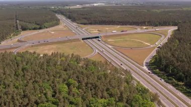 Yüksek açılı insansız hava aracı birden fazla şeritli ve üstgeçitli geniş bir otoyol kavşağını yakalıyor. Geniş yol ağı geniş çam ormanları ve açık çim alanlarıyla çevrilidir..