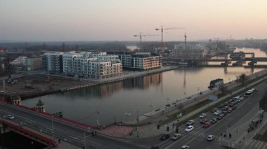 Polonya 'nın Szczecin kentinin hava perspektifi, Odra Nehri boyunca çağdaş kentsel gelişimi sergiliyor. Ön planda, geniş bir yol ve nehir kenarındaki gezinti alanı suya paraleldir. Manzara, yeni ve çağdaş bir konut kompleksini vurguluyor