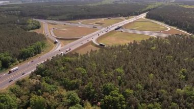 Yüksek açılı insansız hava aracı birden fazla şeritli ve üstgeçitli geniş bir otoyol kavşağını yakalıyor. Geniş yol ağı geniş çam ormanları ve açık çim alanlarıyla çevrilidir..