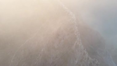 Dağların tepesinde bulutlar arasında uçuyor. Yüksek tepeler, harika sabah güneşi, doğal manzara.