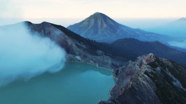 Güneş doğarken sis ve bulutlarla çevrili manzaralı bir sülfür gölü olan İjen yanardağının havadan görünüşü, Kawah Ijen, Java, Endonezya.