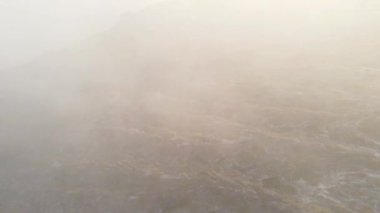 Güneşin muhteşem ışınları bulutların ve sislerin arasından yol alır. Yukarıdaki bulutların arasında uçuyor. Dağlarda sıcak bir gün doğumu. Hava görüntüsü.