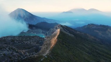 Güneşin doğuşunda sis ve dumanla çevrili çarpıcı bir krater gölü olan güzel Ijen volkanı, Kawah Ijen, Java, Endonezya.