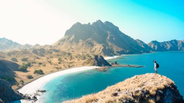  Endonezya 'daki Komodo Ulusal Parkı' ndaki Padar Adası 'nın tepesinden müthiş manzaranın tadını çıkaran genç adam. yaz arkaplanı ve yaz tatili konsepti.