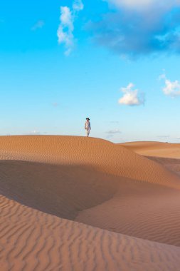 Young men walking in the desert of Dubai, Sand dunes of Dubai United Arab Emirates, sand desert on a sunny day in Dubai