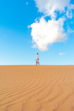 Young men walking in the desert of Dubai, Sand dunes of Dubai United Arab Emirates, sand desert on a sunny day in Dubai.