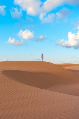 Young men walking in the desert of Dubai, Sand dunes of Dubai United Arab Emirates, sand desert on a sunny day in Dubai