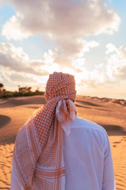 Arap adam gün batımında çölde duruyor.