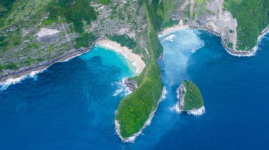 Nusa Penida Bali Endonezya 'da beyaz kumlu sahil Kelingking' i olan kayalık okyanus kıyısı. Açık deniz dalgaları egzotik adaları yıkar.