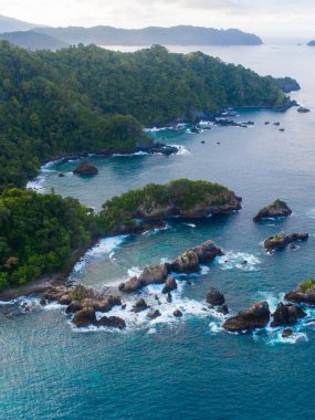 Okyanus manzaralı mavi dalgalar kayalık dağın yüksek uçurumunda kırılıyor.