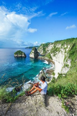Elmas Sahili 'nin tepesinde oturan genç gezgin, Nusa Penida, Bali, Endonezya. yaz arkaplanı ve yaz tatili kavramı. 