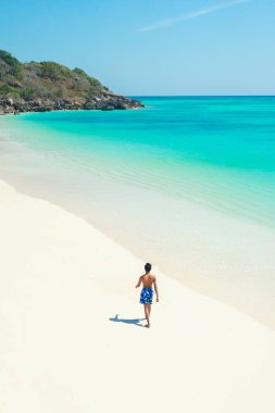 Sahilde deniz manzarasına karşı dinlenen bir adam.