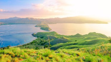 Gün batımında Gili Lawa 'da yeşil tepeli güzel tropikal bir manzara, Endonezya' nın Flores adasındaki Komodo milli parkı. yaz arkaplanı ve yaz tatili konsepti.