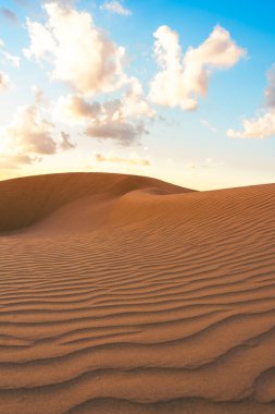 Çöldeki kum tepelerinin üzerinde gün batımı. Sahra Çölü 'nün ıssız manzarası