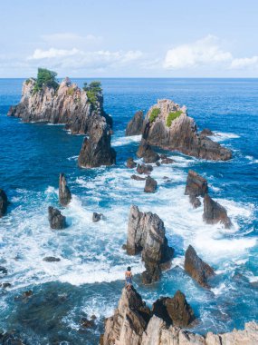 Mavi okyanus dalgalarının bir araya gelişi tropik bir adada kayaya çarpıyor..