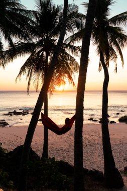 Genç adam gün batımında sahilde dinleniyor..