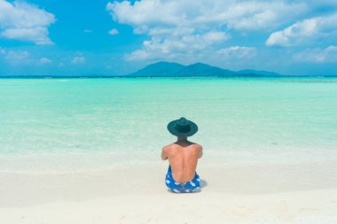 Genç adam plajda güneşin tadını çıkarıyor. Turkuaz tropikal okyanusta. yaz arkaplanı ve yaz tatili kavramı.