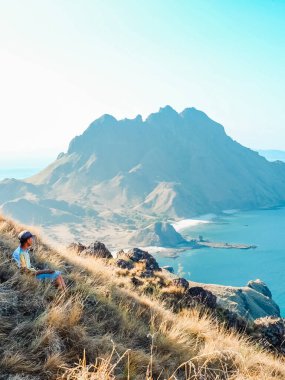 Gezginler dağın tepesinde Padar Adası, Labuan Bajo ve Endonezya 'nın muhteşem manzarasını izliyorlar. yaz arkaplanı ve yaz tatili konsepti.