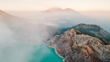 Aerial view of Ijen volcano with a scenic sulfur lake surrounded by mist and clouds at sunrise, Kawah Ijen, Java, Indonesia. clipart