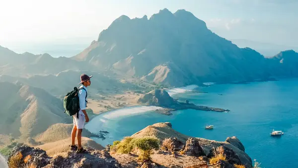Genç turist, Endonezya 'daki Komodo Ulusal Parkı' ndaki Padar adasının tepesindeki güzel manzaranın tadını çıkarıyor. yaz arkaplanı ve yaz tatili konsepti