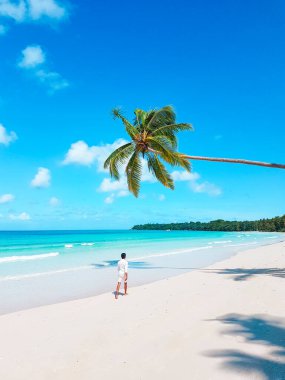 Turkuaz su ve hindistan cevizi ağaçlarıyla tropik bir sahilde yürüyen bir adam. yaz arkaplanı ve yaz tatili konsepti.