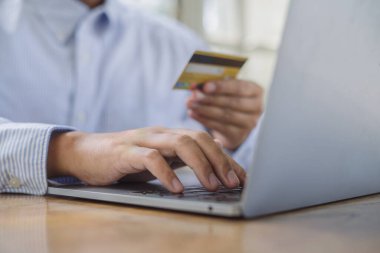 Genç adam ödeme başarısını kredi kartıyla elde ediyor çevrimiçi perakende mağazasından alışveriş yaparken kahve masasında dizüstü bilgisayarla, yaşam tarzı teknolojisiyle