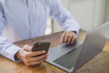 İşadamı cep telefonu kullanıyor. Bilgisayarda ve tablette çalışıyor. İnternette geziniyor, ofisteki bilgileri araştırıyor.