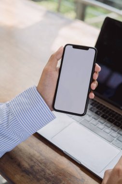Masasında akıllı telefon maketi kullanan bir adamın elleri. Grafikleri düzenlemek için cep telefonu boş ekran.