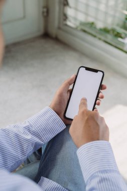 Bir kişi cep telefonunu tutuyor ve ekranı işaret ediyor. Telefon beyaz ve kişinin elleri görünür durumda.. 