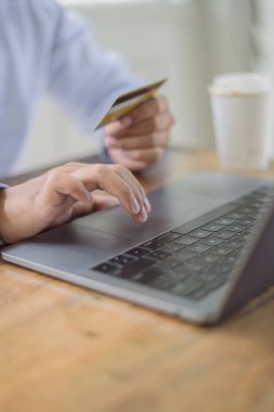 Genç adam ödeme başarısını kredi kartıyla elde ediyor çevrimiçi perakende mağazasından alışveriş yaparken kahve masasında dizüstü bilgisayarla, yaşam tarzı teknolojisiyle