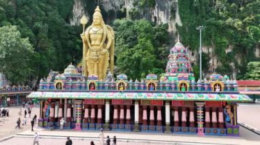 Kuala Lumpur, Malezya - 05.23.2024: Batu Mağaralarının arka planında Lord Murugan 'ın altın heykeli olan Hint tapınağı. Dini mekan ve popüler turistik mekan.