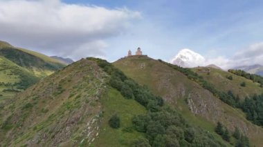 Gürcistan 'ın Stepantsminda köyü yakınlarındaki Kafkasya Dağları' ndaki Gergeti Trinity Kilisesi 'nin hava manzarası. Kazbek Dağı ve karla kaplı görkemli tepeler.